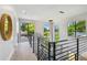 Upstairs hallway featuring hardwood floors, metal railings, and an abundance of natural light from large windows at 715 W Peninsular St, Tampa, FL 33603