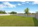 Large backyard with a green lawn, privacy fence, and scenic water view beyond the fence at 10142 Golden Wonder Ln, Riverview, FL 33578