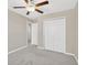 Cozy bedroom with gray carpet, ceiling fan, and a spacious closet with bi-fold doors at 10142 Golden Wonder Ln, Riverview, FL 33578