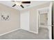 Bedroom with gray carpet, ceiling fan, closet, and adjacent hallway, offering comfortable living space at 10142 Golden Wonder Ln, Riverview, FL 33578