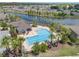 Aerial view of a sparkling community pool with palm trees, lounge chairs and lush landscaping near a pond at 10142 Golden Wonder Ln, Riverview, FL 33578