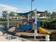 The colorful train themed playground with a shade sail overlooks the grassy lawn and the lake in this neighborhood at 10953 Winter Crest Dr, Riverview, FL 33569