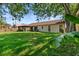 Large backyard featuring a lush green lawn, mature trees, a screened-in porch, and a wooden fence at 1308 Peachfield Dr, Valrico, FL 33596