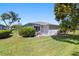 Grassy backyard featuring mature landscaping, a screened lanai, and views of the home's exterior at 1416 Leland Dr # 49, Sun City Center, FL 33573