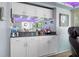 Sunroom wet bar featuring granite countertop, white cabinetry and mirrored backsplash at 1416 Leland Dr # 49, Sun City Center, FL 33573