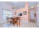 Dining area with large table, statement chandelier, view of the front door, and a kitchen pass through, and pink accent wall at 2139 Elm St # 308, Dunedin, FL 34698