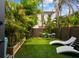 Landscaped backyard featuring green turf, tropical plants, lounge chairs, and a table set for relaxing outdoors at 2505 W Azeele St, Tampa, FL 33609