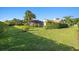 Expansive backyard featuring lush green grass, tropical landscaping, and a screened pool enclosure at 2886 Green Meadow Ct, Clearwater, FL 33761