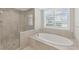 Bright bathroom with a walk-in shower, soaking tub, shuttered window and white cabinets at 300 Beach Ne Dr # 401, St Petersburg, FL 33701