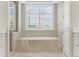 Bright bathroom with a soaking tub, tiled surround, shuttered window and white cabinets at 300 Beach Ne Dr # 401, St Petersburg, FL 33701