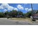 Exterior view of modest home with siding, a yard with mature trees, and a partially fenced in area at 4207 E Henry Ave, Tampa, FL 33610