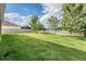 Spacious, green backyard featuring a well-maintained lawn, mature trees, and a white picket fence at 5416 Camberwell Ln, Riverview, FL 33578
