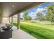 Covered back patio with furniture overlooking a spacious, well-maintained backyard with a scenic lake view at 5416 Camberwell Ln, Riverview, FL 33578