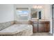 Bright bathroom featuring soaking tub with tiled surround, double sink vanity, and ample natural light at 5416 Camberwell Ln, Riverview, FL 33578