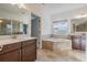 This well-lit bathroom features a soaking tub, tiled floors, double sink vanity, and a glass-enclosed shower at 5416 Camberwell Ln, Riverview, FL 33578