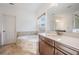 Bright bathroom featuring double sink vanity, soaking tub with stone surround, and a window allowing natural light at 5416 Camberwell Ln, Riverview, FL 33578