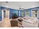 Bright living room features tile flooring, blue walls, large windows, and cozy seating at 5416 Camberwell Ln, Riverview, FL 33578