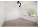 Simple bedroom with carpet, ceiling fan, and window overlooking a bright outdoor space at 5547 Silver Sun Dr, Apollo Beach, FL 33572