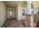 Covered front porch featuring stone pillars, brick flooring, and a stylish front door at 5547 Silver Sun Dr, Apollo Beach, FL 33572