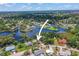Aerial view of a waterfront property with dock and a pool surrounded by trees in a developed residential neighborhood at 5761 Colonial Dr, New Port Richey, FL 34653