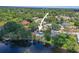 Aerial view of a single-Gathering home, dock, and pool surrounded by lush greenery and a lake in a quiet neighborhood at 5761 Colonial Dr, New Port Richey, FL 34653