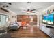 Cozy living room featuring a wood accent wall, ceiling fan, stylish furniture, and a large TV at 5761 Colonial Dr, New Port Richey, FL 34653