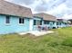 Charming home exterior featuring a blue facade, a brown roof, a green lawn, and a patio with outdoor seating at 6880 Versailles N, Pinellas Park, FL 33781