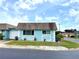 Charming single story home with a light blue exterior, flower pots and landscaping at 6880 Versailles N, Pinellas Park, FL 33781