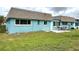 Charming home exterior featuring a blue facade, a brown roof, a green lawn, and a patio with outdoor seating at 6880 Versailles N, Pinellas Park, FL 33781