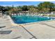 Large community pool with clear blue water, surrounded by ample lounge chairs and lush greenery under a blue sky at 6880 Versailles N, Pinellas Park, FL 33781
