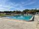 Large community pool with clear blue water, surrounded by ample lounge chairs and lush greenery under a blue sky at 6880 Versailles N, Pinellas Park, FL 33781