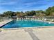 Large community pool with clear blue water, surrounded by ample lounge chairs and lush greenery under a blue sky at 6880 Versailles N, Pinellas Park, FL 33781