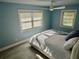 Comfortable bedroom with two bright windows, ceiling fan, and stylish light blue walls at 8025 Island Dr, Port Richey, FL 34668
