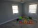 Bright bedroom with a fun alphabet mat and playful decor, with two windows and light-colored walls at 8025 Island Dr, Port Richey, FL 34668