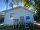 A light blue home with a small door and window and various items stacked around the side of the house at 8203 N Semmes St, Tampa, FL 33604