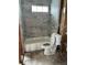 Bathroom tub/shower combo featuring updated gray marble-patterned tiling, along with glass shelves at 844 Bruce Ave, Clearwater Beach, FL 33767
