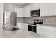 Modern kitchen featuring stainless steel appliances, white cabinets, and granite countertops at 9066 Rally Spring Loop, Wesley Chapel, FL 33545