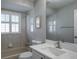 Bright bathroom featuring vanity with white marble countertop, tiled shower, and window with plantation shutters at 9500 Green Needle Dr, New Port Richey, FL 34655