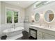 Bright bathroom featuring a standalone tub, marble wall, vanity, and double mirrors at 1014 7Th Street N, St Petersburg, FL 33701
