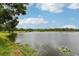 Scenic lakeside view of calm waters surrounded by green lawns and mature trees against a partly cloudy sky at 1014 7Th Street N, St Petersburg, FL 33701
