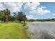 Picturesque lakeside view with vibrant green grass and mature trees under a blue, cloudy sky at 1014 7Th Street N, St Petersburg, FL 33701