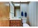 Vintage bathroom with mirror, wallpaper, overhead lighting, and storage under a sink at 107 Garland Cir, Palm Harbor, FL 34683