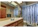 Neutral-toned bathroom showcases a mirror, sink, shower with patterned curtain, and wood-look cabinets at 107 Garland Cir, Palm Harbor, FL 34683