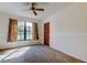 Empty carpeted bedroom features natural light, a ceiling fan, and a closet with louvered doors at 107 Garland Cir, Palm Harbor, FL 34683