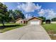Charming single-story home featuring a two-car garage, concrete driveway, and lush green lawn at 107 Garland Cir, Palm Harbor, FL 34683