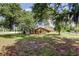 Spacious backyard featuring mature trees and partial view of the house with warm tones at 107 Garland Cir, Palm Harbor, FL 34683