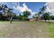 Wide front yard of this home with mature trees, well maintained lawn, and privacy fence in the background at 107 Garland Cir, Palm Harbor, FL 34683