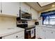 Cozy kitchen features white cabinets, stainless steel appliances, and window over the sink at 107 Garland Cir, Palm Harbor, FL 34683