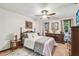 Comfortable bedroom featuring a wood frame bed, ceiling fan, dresser, carpeted floors, and natural lighting through windows at 11209 Spring St, Largo, FL 33774