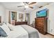 Comfortable bedroom featuring a wood frame bed, ceiling fan, dresser, carpeted floors, and natural lighting through windows at 11209 Spring St, Largo, FL 33774